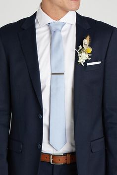 a man in a suit with a blue tie and flower boutonniere on his lapel