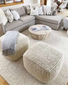 a living room filled with lots of furniture and pillows on top of a white rug