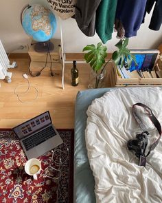 a laptop computer sitting on top of a bed next to a lamp and other items