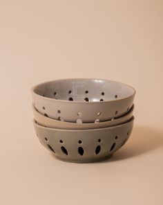 three bowls stacked on top of each other with holes in the bottom one bowl is gray and the other white