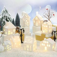 a group of small houses with lights on them in the middle of snow covered ground