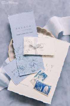 blue and white wedding stationery laid out on top of each other in a bowl