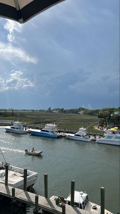 boats are docked in the water near a dock with an umbrella over it's head