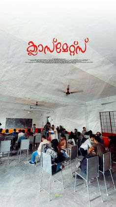 there are many people sitting at desks in the room with red writing on the ceiling