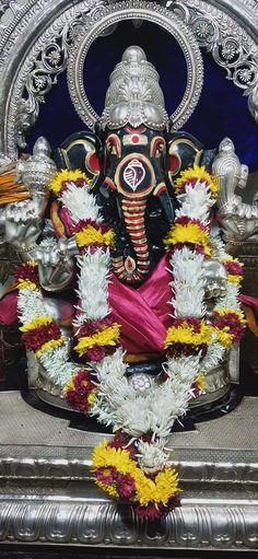 an idol is sitting in the middle of a stage with flowers around it and other decorations