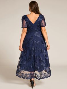 a woman wearing a blue dress with sheer sleeves and floral lace on the bouncy