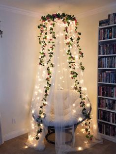 a bed covered in white netting with lights on it and flowers hanging from the ceiling