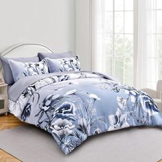 a bed with blue and white flowers on it in a room next to a window