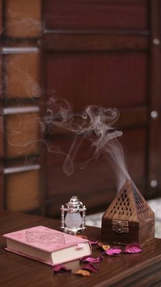 a wooden table topped with a book next to a candle and smokestack on top of it