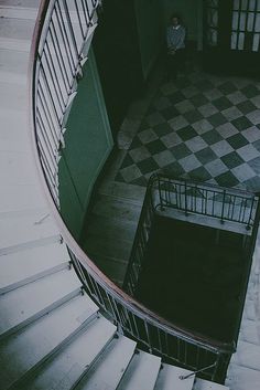 an overhead view of a spiral staircase with a person standing in the doorway behind it