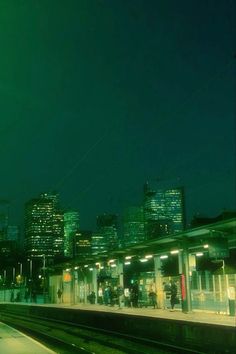 a train station at night with people waiting on the platform