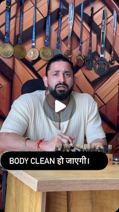 a man sitting at a desk with medals on the wall behind him and an ad for body clean in front of him