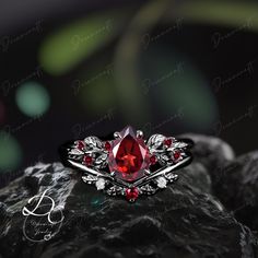 a ring with a red stone surrounded by leaves