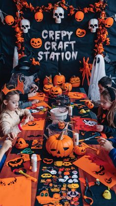 two children sitting at a table decorated with halloween decorations and paper pumpkins for creepy craft station