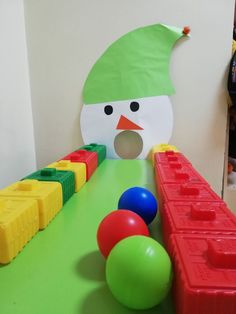 a snowman made out of plastic blocks and balls on the floor next to a play table