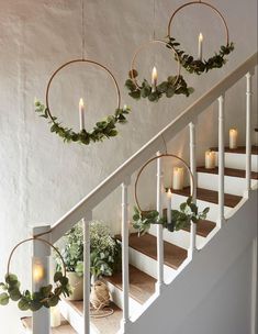 some candles are hanging on the stairs with wreaths and greenery around them for decoration