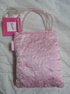 a pink purse sitting on top of a bed next to a tag with the word hello kitty written on it