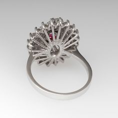 This stunning vintage ring is crafted of platinum and features a orangey red ruby surrounded by baguette and round diamonds. The ruby is rich and vibrant, and is completely natural and unheated. The diamonds are all high quality and eye clean. The ring is currently a size 6.5 and we offer complimentary resizing to fit. Red Ruby Ring With Baguette Diamonds, Red Ruby Ring With Halo Setting In Platinum, Red Diamond Ring With Halo Setting In Platinum, Red Baguette Diamond Wedding Rings, Red Baguette Diamond Rings For Anniversaries, Red Baguette Diamond Rings For Anniversary, Wedding Rings With Ruby And Baguette Diamonds, Fine Jewelry Ruby Ring With Baguette Diamonds For Wedding, Formal Ruby Ring With Baguette Diamonds