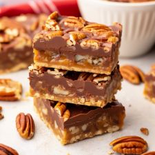 three pieces of pecan bar stacked on top of each other with nuts around them