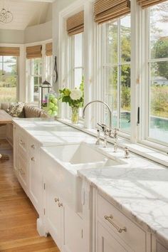 a large kitchen with white cabinets and marble counter tops