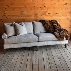 a couch with some pillows on it in front of a wood paneled wall and floor