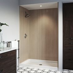 a bathroom with a walk in shower next to a white sink and brown cabinetry