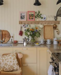 a kitchen filled with lots of counter top space and flowers in vases on the shelves