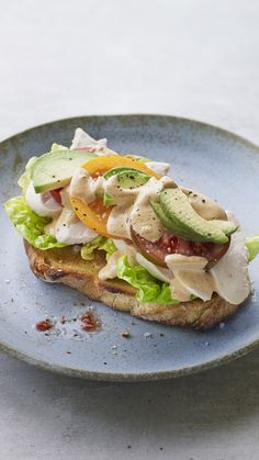 a sandwich with lettuce, tomato and cucumber on it sitting on a blue plate