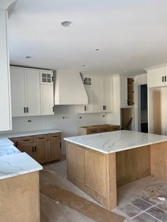 an empty kitchen with white cabinets and marble counter tops in the middle of the room