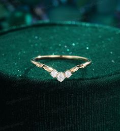 a diamond ring sitting on top of a green velvet covered cushioned surface with sparkles in the background