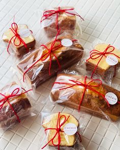 several pieces of bread wrapped in cellophane and tied with red ribbon on a white tiled surface