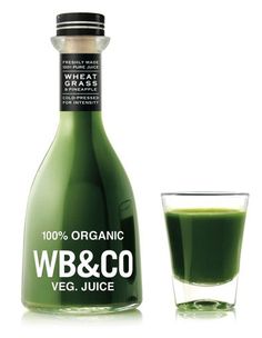 a bottle of w b & co juice next to a glass filled with green liquid