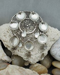 This is the perfect option for those who like cool, unique jewelry, and the luxury, shine of sterling. Vintage Norwegian J 830 Silver Pin Brooch. Composed of filigree circle and 7 cascade of silver filigree with spoons which manages to catch & reflect light beautifully (also reflect negativity & evil) with a simple movement. Is Norway's traditional silver jewelry. Its dangling spoons once were thought to reflect evil. Away from the wearer, protecting one from trolls and other dangers, es Silver Bohemian Brooches For Collectors, Silver Bohemian Brooch Jewelry, Silver Bohemian Jewelry Brooch, Handmade Silver Pendant Brooch, Unique Sterling Silver Brooch In Silver, Handmade Silver Pendant Brooches, Handmade Silver Bohemian Brooch, Intricate Pendant Brooches As Gifts, Unique Silver Pendant Brooch