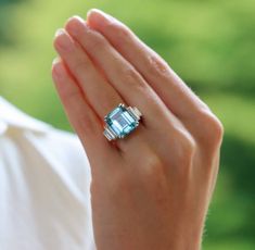 a woman's hand holding an engagement ring with a blue topazte stone