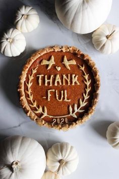 a pumpkin pie with the words thank you written on it and white pumpkins around it