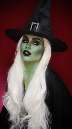 a woman with long white hair wearing a witches hat and green makeup on her face