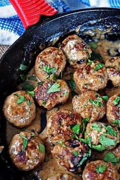 a skillet filled with meatballs covered in gravy and garnished with parsley