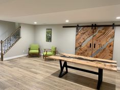 a large wooden table sitting in the middle of a room next to two green chairs