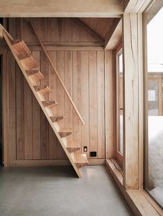 a wooden staircase leading up to a bed in a room with wood paneled walls