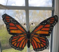 a stained glass butterfly hanging from a window