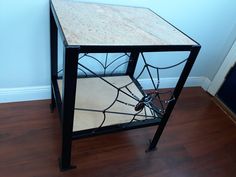 a small table with a glass top and metal legs on the floor in front of a blue wall