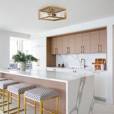 a kitchen with marble counter tops and gold stools in front of an island bar