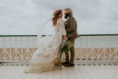 a bride and groom standing next to each other in front of the ocean on their wedding day