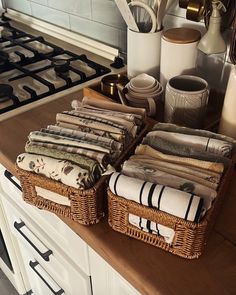 towels are stacked on top of wicker baskets in the kitchen, next to utensils