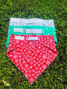 three bandanas laying on the grass in front of each other, one red and one blue