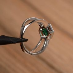 It is a lab emerald ring. The main stone is 7mm*7mm round cut, weight about 1.3 carats. The basic metal is sterling silver and plated with rhodium. To change the metal to a solid gold (white/rose) or platinum is also available, please ask for a quotation if you want. You can also go to my shop Home for more elegant rings: https://www.etsy.com/shop/godjewelry?ref=hdr_shop_menu More lab emerald rings: https://www.etsy.com/shop/godjewelry?ref=seller-platform-mcnav&section_id=20709240 Customizat Green Emerald Ring In Sterling Silver With Halo Setting, Silver Solitaire Emerald Rings, Emerald Ring In Sterling Silver With Round Band, White Gold Emerald-cut Cubic Zirconia Ring, White Gold Emerald Cut Cubic Zirconia Ring, Fine Jewelry With Halo Setting For May Birthstone, May Birthstone Jewelry With Halo Setting, Fine Jewelry Emerald Ring With Bezel Setting, Round Cut, Fine Jewelry Emerald Ring With Bezel Setting