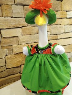 a green dress with an orange flower on the top and a white headdress