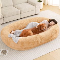 a woman laying on top of a dog bed in a living room next to a couch