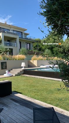 a house with a swimming pool in the middle of some grass and plants on the ground