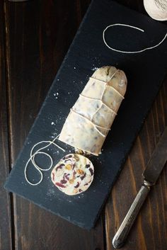 a piece of bread sitting on top of a black cutting board next to a knife